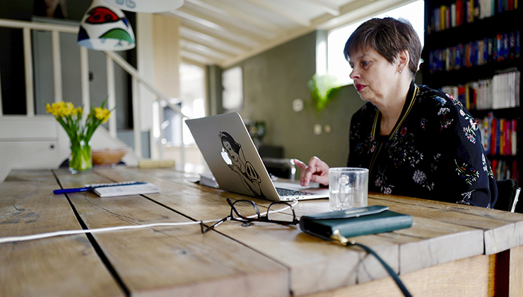 Een vrouw telewerkend aan de keukentafel