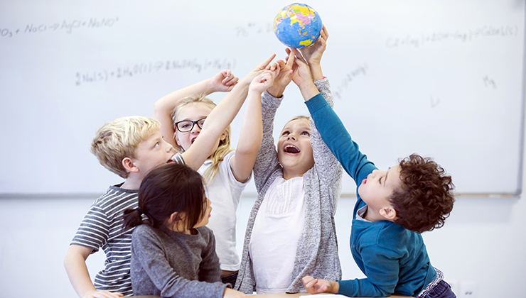 meerdere kinderen houden een wereldbol vast boven zichzelf in de lucht